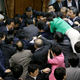 Opposition lawmakers and ruling lawmakers mob around Yoshitada Konoike. The legislator in green is Hiroe Makiyama. EPA/Kimimasa Mayama